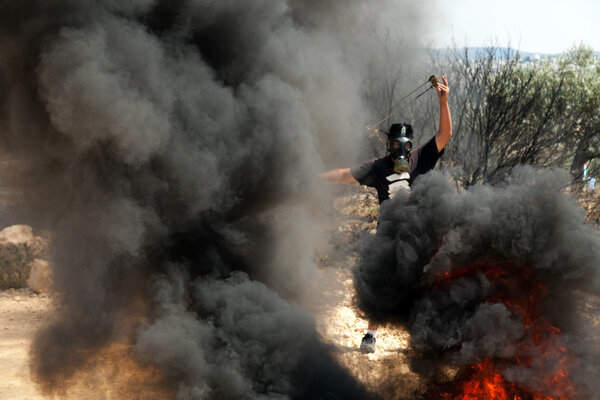 Palestinian Protester with Slingshot Amidst Smoke