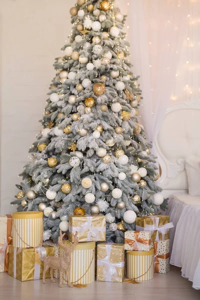 Photo of luxury gift boxes under Christmas tree, New Year home decorations, golden wrapping of Santa presents, festive tree decorated with garland, baubles, traditional celebration — Stock Photo, Image