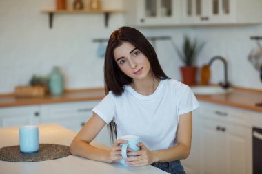 Güzel genç bayan evde bir fincan kahve içiyor..