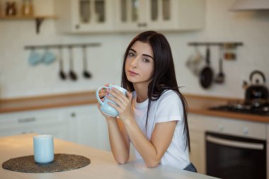 Güzel genç bayan evde bir fincan kahve içiyor..