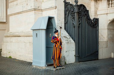 VATICAN CITY - MAY 22 2017 : Pontifical Swiss Guard securing one access of St. Peters Basilica clipart