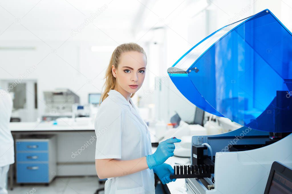 A medical worker works in an auto-biochemical and immune enzyme analyzer in the laboratory of the clinic