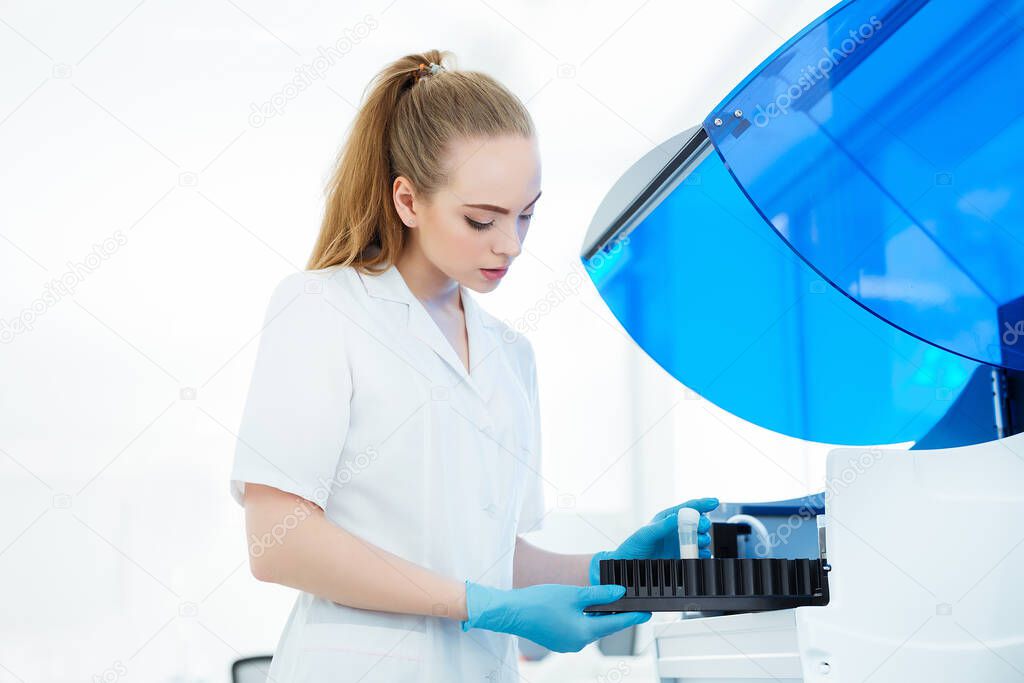 A medical worker works in an auto-biochemical and immune enzyme analyzer in the laboratory of the clinic