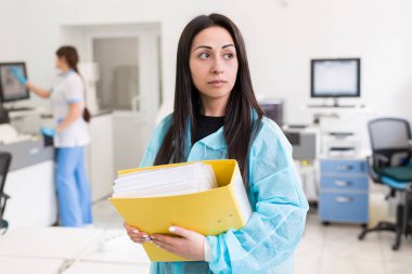 Modern laboratuarda tıbbi araştırma yapan çekici kadın bir laboratuvar çalışanı. Analiz sonuçlarıyla birlikte belge dizini tutan bilim adamı