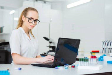 Modern teknoloji bilimde. Araştırma sonuçlarını laboratuvarda dizüstü bilgisayara giriş yapan bilim adamı.