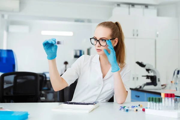 Scientist analyzing microscope slide at laboratory. Female Working in Laboratory With Microscope. Researcher examining slide. Concenrated doctor working with microscope in laboratory.