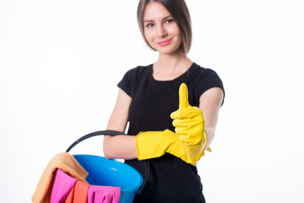 Happy young woman holding a bucket filled with cleaning products isolated on white background.