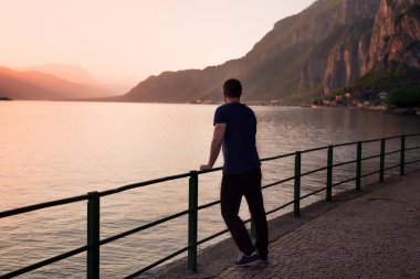 Destansı manzara bir erkek figürüyle tamamlanmış. Dağ, göl ve gökyüzü gün batımının parlak renkleriyle.