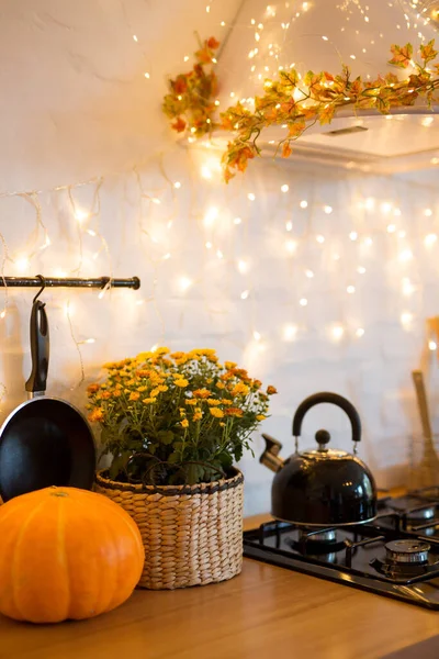 Autumn kitchen interior. Red and yellow leaves and flowers in the vase and pumpkin on white background.