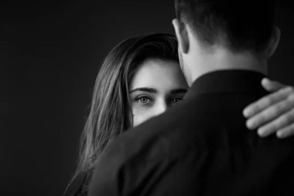 Love and care concept. Beautiful brunette woman with bright eyes looks on her boyfriend. Couple embrace. Black and white image