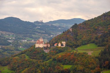 Tepedeki küçük şirin dağ köyü, arka plandaki Dolomites dağları İtalya 'daki Odle ve Seceda zirveleri