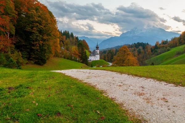 圣母玛利亚教堂座落在山后 而沃兹曼山脉则是秋色的日落时分 德国巴伐利亚 伯克特斯加登 — 图库照片