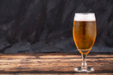 Koyu ahşap arka planda taze açılmış hafif bira bardağı.