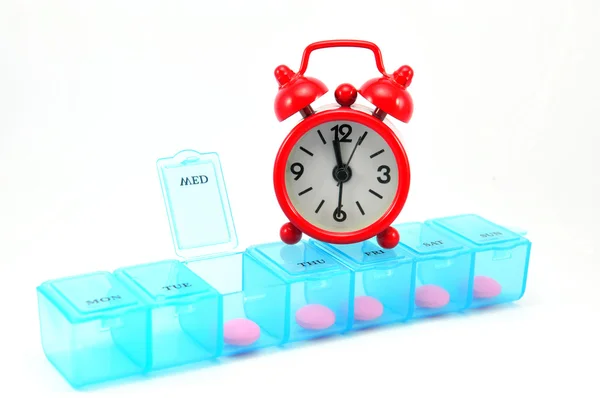 Dialy pill box and red clock on white blackground — Stock Photo, Image