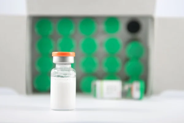 Frasco para injectáveis de tampa laranja sobre o fundo dos frascos verdes — Fotografia de Stock