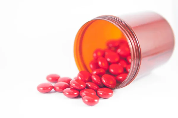 Red tablet and brown prescription bottle — Stock Photo, Image