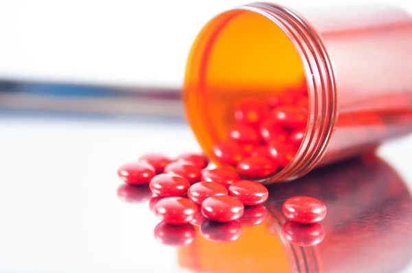 Coated red tablet and brown bottle on dispensing tray — Stock Photo, Image
