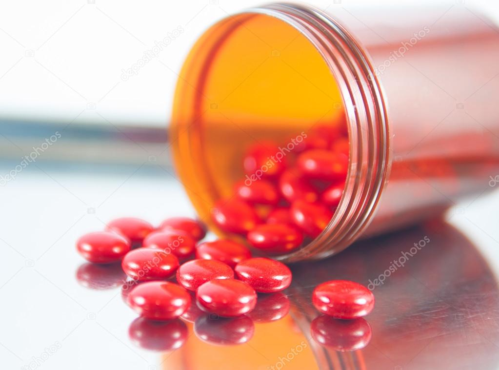 Coated red tablet and brown bottle on dispensing tray