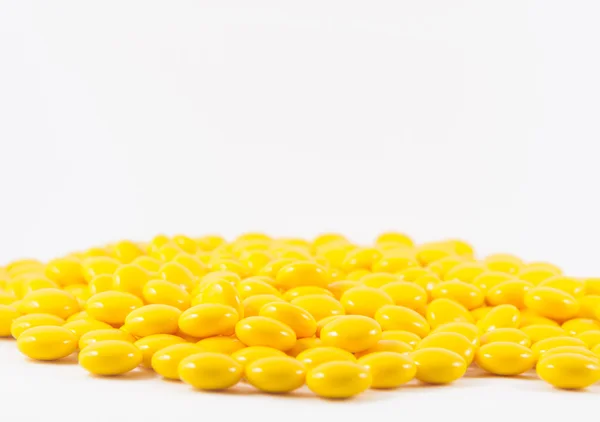 Coated yellow tablet on white — Stock Photo, Image