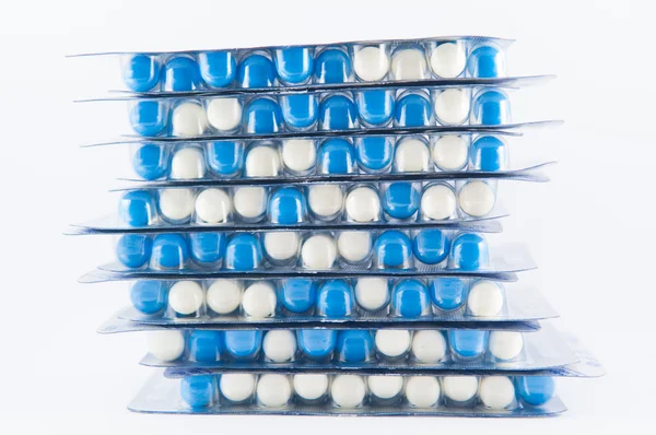 Uzavřeno vrstva modrými a bílými kapsle v blistru na bílém pozadí — Stock fotografie