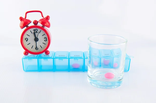 Red clock and prescription pill box show medicine time concept — Stock Photo, Image