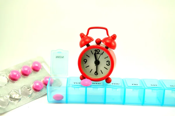 Weekly pill box and red clock on white blackground — Stock Photo, Image