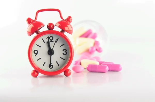 Red clock and medicine tablet on white blackground — Stock Photo, Image