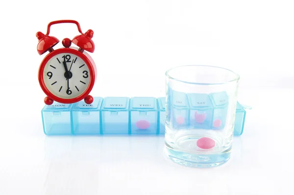 Pink tablet and redclok in daily pill box — Stock Photo, Image