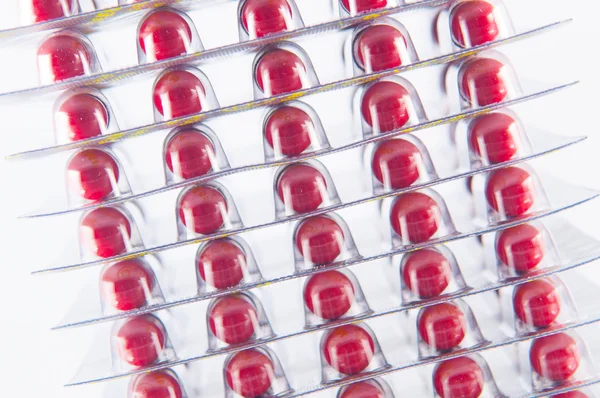 Слой красной капсулы в блистерной упаковке на белом шоу медицины conc — стоковое фото