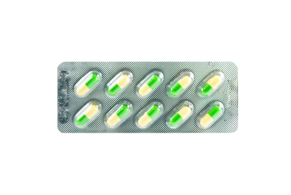 Closed yellow and green capsule in blister pack on white — Stock Photo, Image
