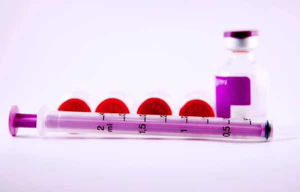 Purple disposable syringe on injection vials — Stock Photo, Image