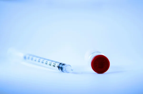 Disposable syringe and side of red cap vial — Stock Photo, Image
