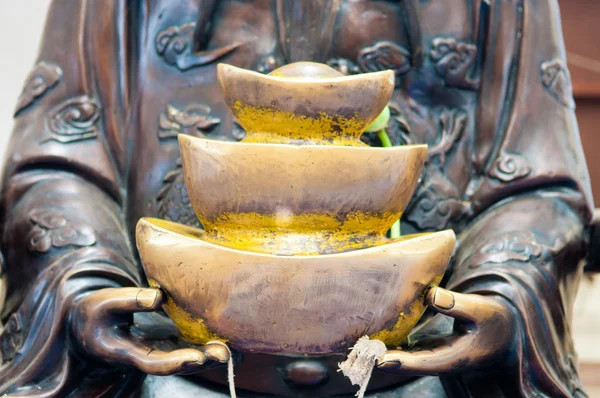 La estatua negra sostiene el lingote de oro chino en la mano —  Fotos de Stock