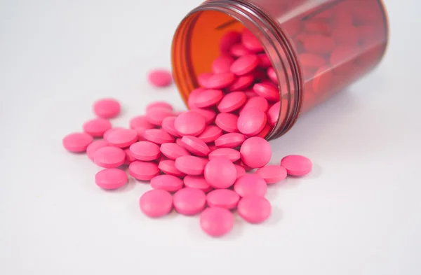 Pink tablet fall from dispensing bottle — Stock Photo, Image