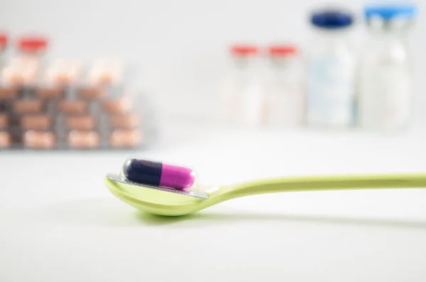 Purple and blue capsule in blister pack in spoon — Stock Photo, Image