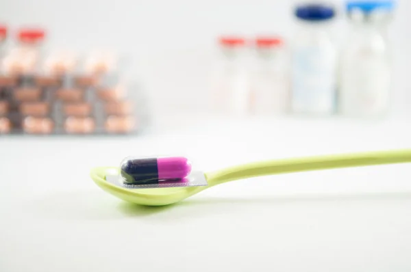 Purple and blue capsule in blister pack in spoon — Stock Photo, Image