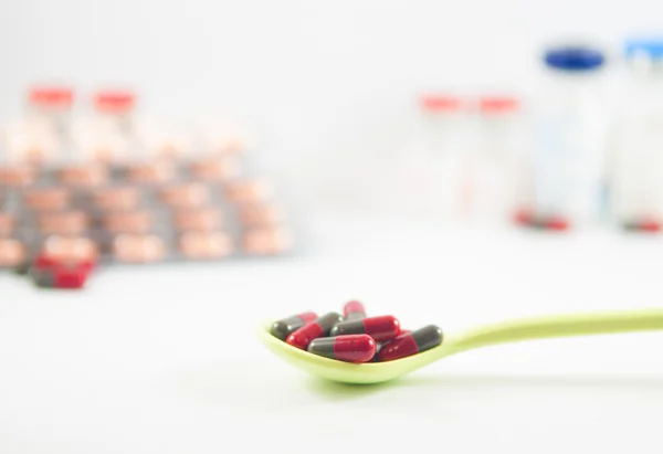 Red and gray capsule in spoon on medicine background — Stock Photo, Image