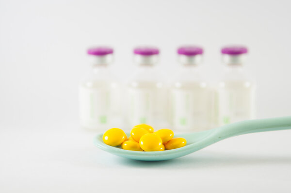 Таблетка с желтым покрытием в ложке
