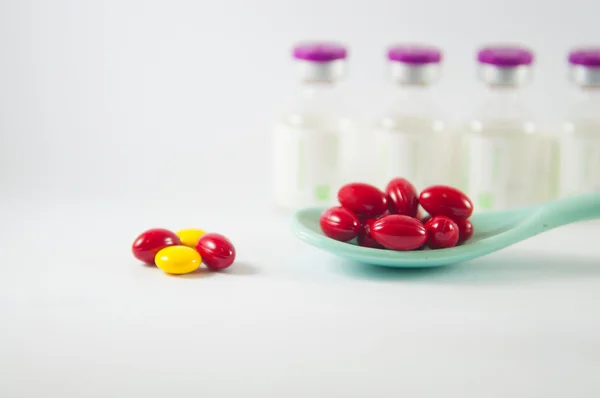 Comprimido vermelho na colher no fundo dos frascos para injetáveis de medicamento — Fotografia de Stock