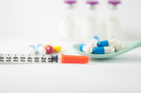 Disposable syringe on injection vials and capsule in spoon — Stock Photo, Image