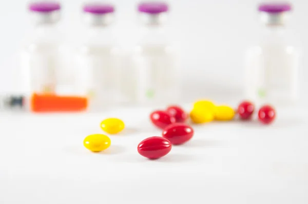 Красная таблетка на фоне лекарственных пузырьков — стоковое фото