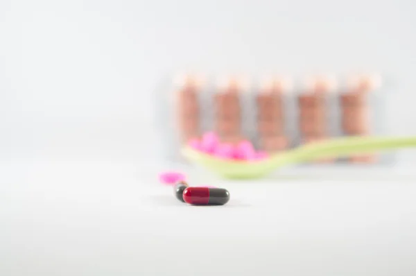 Röd och grå kapsel och tablet i sked bakgrund — Stockfoto