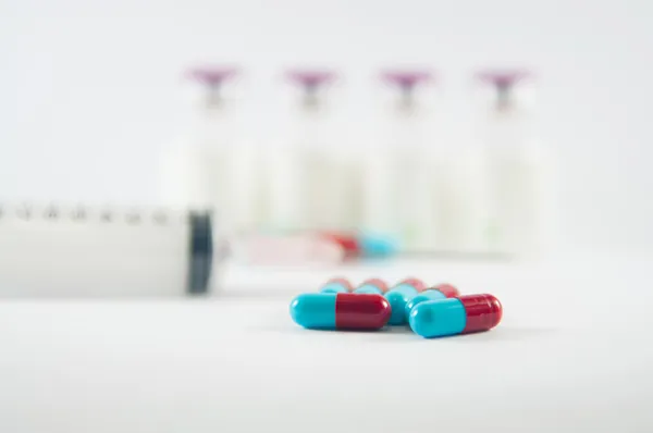 Rote und blaue Kapsel und Spritze zeigen medizinisches Konzept — Stockfoto