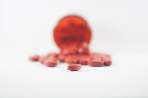 Коричневые таблетки на фоне бутылки с лекарством — стоковое фото