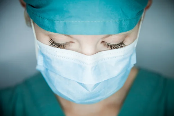 Läkare i en mask som ser på patienten — Stockfoto