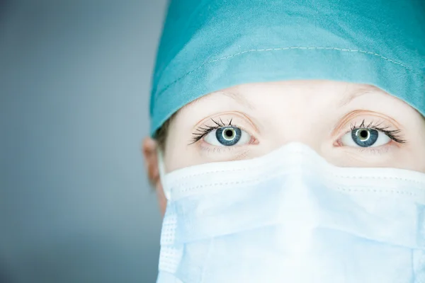 Arzt mit Maske schaut Patient an Stockbild