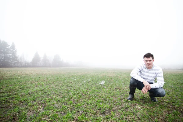 Young man In the foggy field — Stok fotoğraf