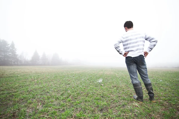 Young man In the foggy field — Stok fotoğraf