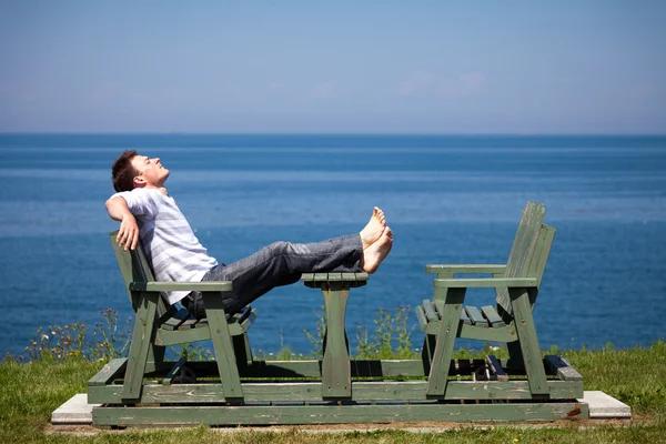 Jonge man die op het strand zit — Stockfoto