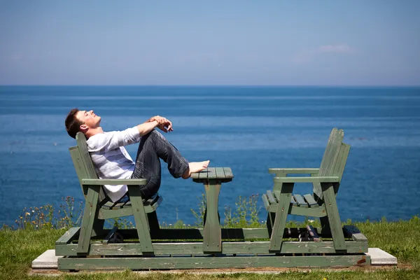 Junger Mann sitzt am Strand — Stockfoto